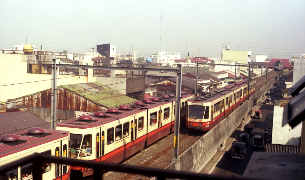 06811 (298) 08-11-1994 Manila Light Rail coupled articulated train sets 1056 + 1055 passing 1017 + 1018 at Tayuman, Santa Cruz, Manila, Philippines.