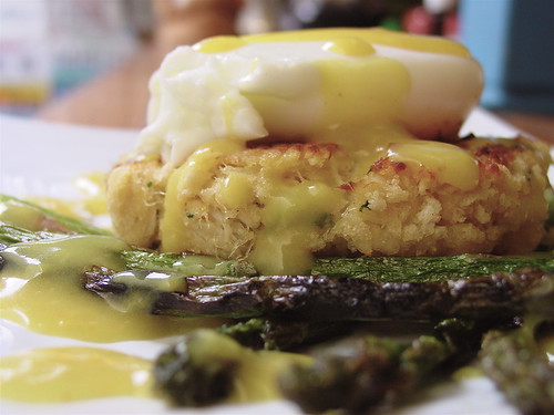 poached egg on hashbrown round topped with hollandaise sauce with asparagus on the side