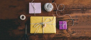 wrapped gifts with string and paper tape scissors on wood table | by PersonalCreations.com