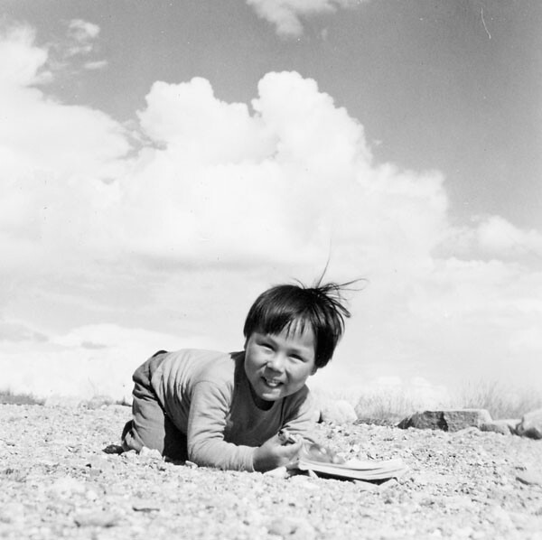 Young Inuk kneeling on the ground and smiling, Qamanittuaq, Nunavut / Le jeune Inuk agenouillé sur le sol et souriant, à Qamanittuaq (Nunavut)