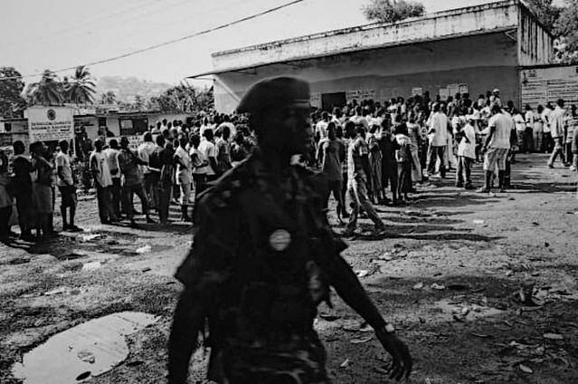Past & Present - Freetown, Sierra Leone 2012- As people line up peacefully to cast there votes a soldier passes between me and the voters... A reminder that elements of the past still  loom... #onedailyfoto #streetphotography #photojournalism #documentary