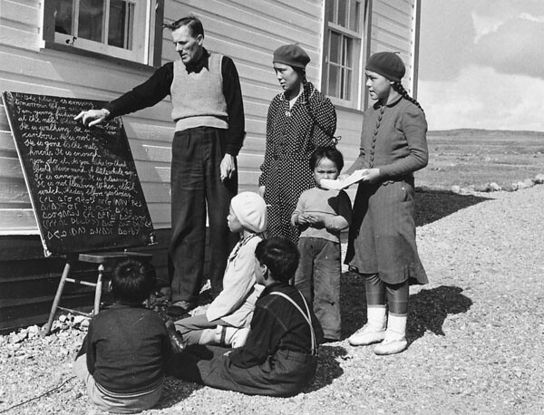 Anglican missionary Reverend W. James teaching his class of Inuit students how to read Inuktitut syllabics... / Le révérend W. James, missionnaire anglican, enseignant à sa classe d’étudiants inuits l’écriture syllabique de l’inuktitut...