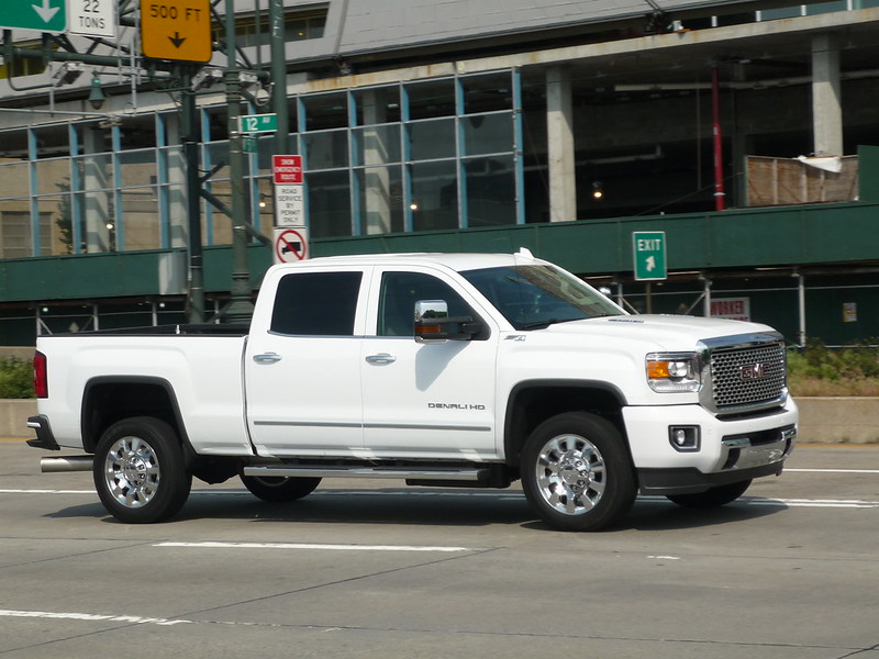 White GMC truck driving through a city highway entrance