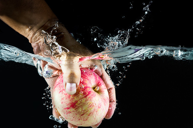 hand take up Apple splashing in water.