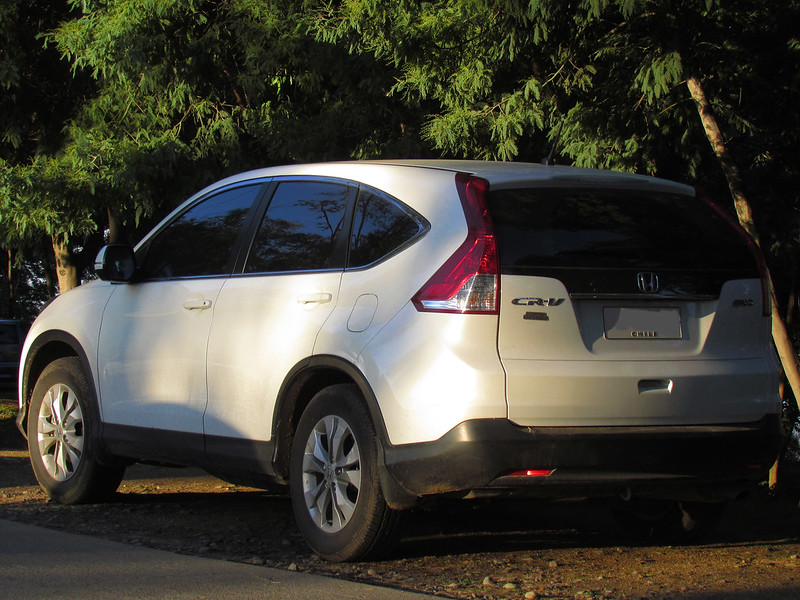 White Honda CR-V parked in parking lot surrounded by trees