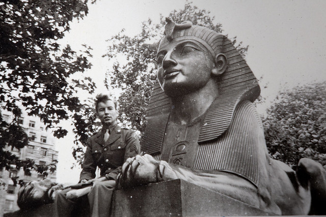 1940s World War II snapshot photo of American soldier tech sergeant Bahr of the 9th United States Army Air Forces, USAAF, 6th TAC Tactical Air Command in London, England.  USAAF Tech sergeant Bahr is sitting by one of Cleopatra’s Needle Sphinxes