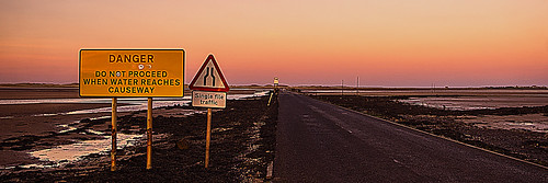 sunset lindisfarne causeway road tide water north sea sign signs straightroad
