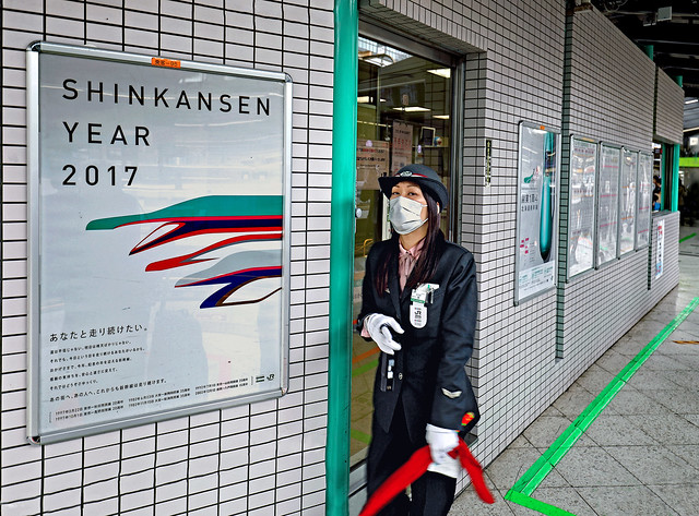 Japan 2017. Kyoto. Japan Rail's Female agent aside the poster for the Shinkansen Year.