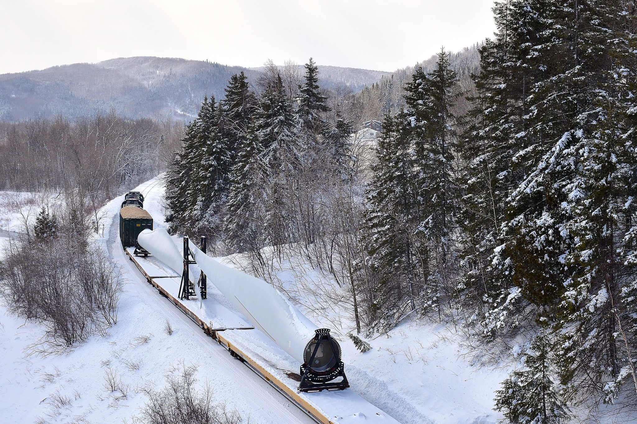 The Société du chemin de fer de la Gaspésie's windmill train is arriving in Matapedia where interchange with the CN will take place as it passes under a bridge where all the railfans chasing this train assembed for a final action shot.