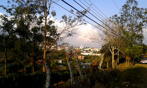 cableado árboles paisaje vegetación rural pueblo edificios camino poste cafetales colina cielo nubes atardecer vehículo