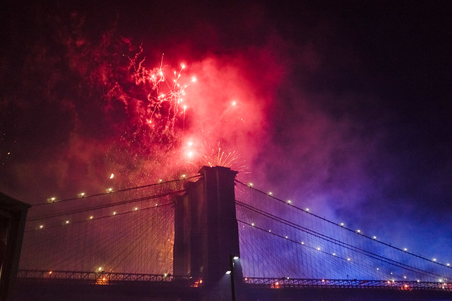 Red bursts, blue smoke, along the Brooklyn Bridge