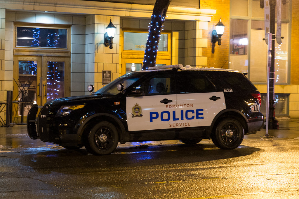 An Edmonton police SUV parked on a well-lit street on a wet evening]