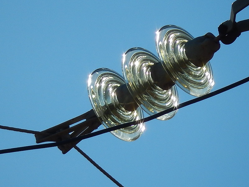 Clear circular connectors on dark cables against a blue sky background