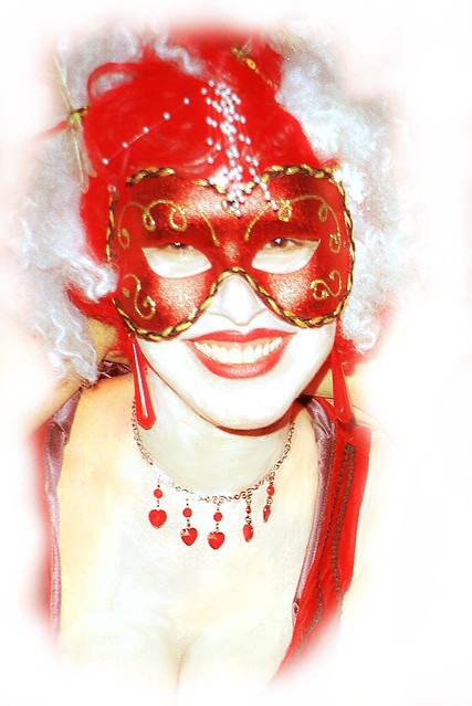 Beautiful blonde woman in a red mask dressed for a ball or Halloween party.