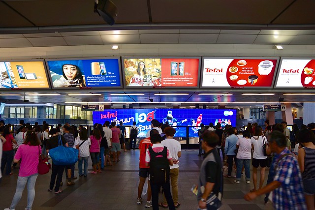 BTS Skytrain Central station with lots of people waiting for the next train and plenty of advertising boards