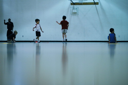 Four children playing on an basketball court in a YMCA in McKinney.