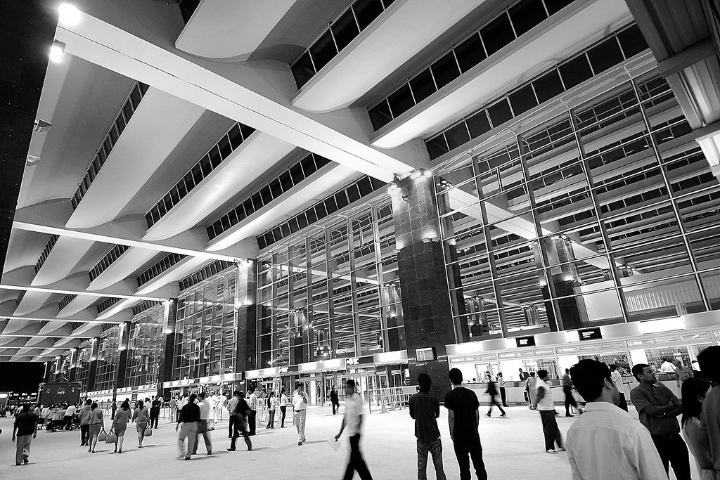 Passengers beneath a high airport terminal roof