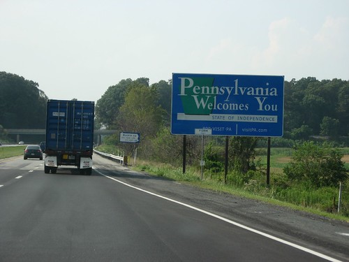 Vehicles driving past the Pennsylvania Welcomes You sign