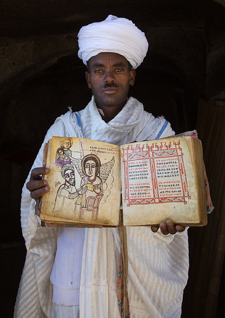 Priest of the ethiopian orthodox church in Asheten mariam rock hewn church with an old bible, Amhara region, Lalibela, Ethiopia