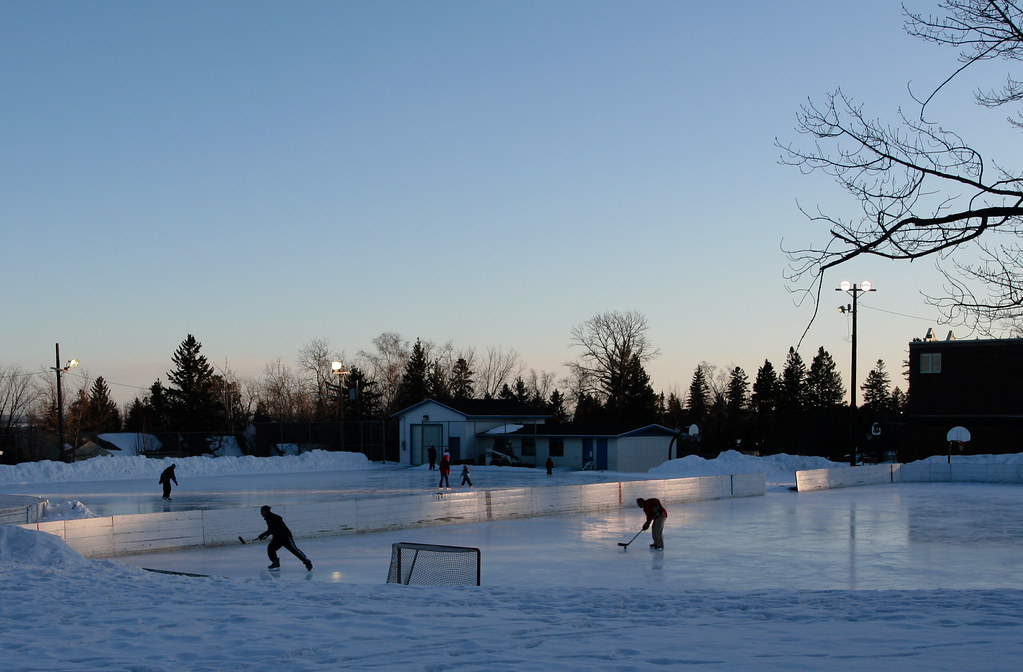 People playing hockey on outdoor ice rink at night