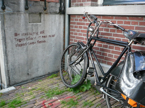 La leyenda en la pared dice en holandes algo bonito sobre dos bicicletas descansando en la pared, como lo estan haciendo