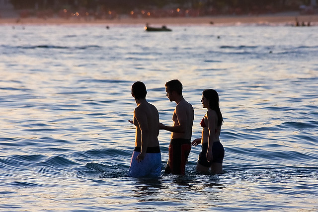 Two boys and one girl get in the water in Guaruja