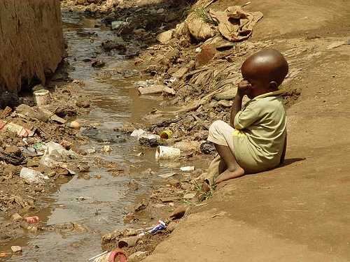 Child in slum in Kampala (Uganda) next to open sewage