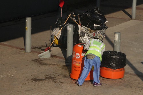 Cleaner emptying a street rubbish bin