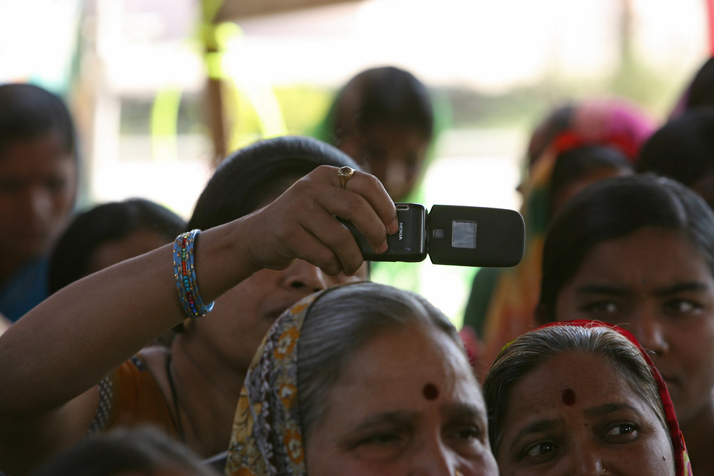 Woman takes photo with cellphone at a community meeting