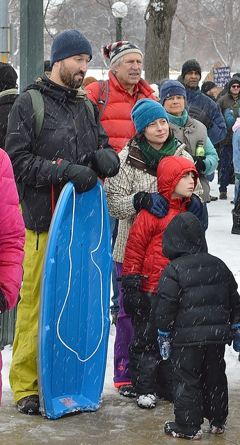 Parents and their children wait in the snow for MLK Day parade to start.
