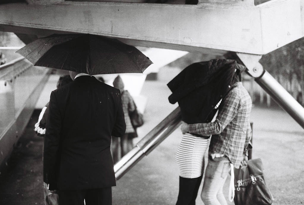 Black and white film capture of two a couple in the rain from the album by Barry Khan, Rainy London Days