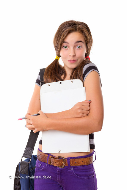 teenage girl with clipboard and pencil smiling, isolated on white
