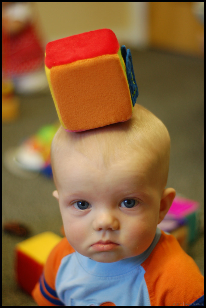 Baby balanciert Spielzeug auf dem Kopf