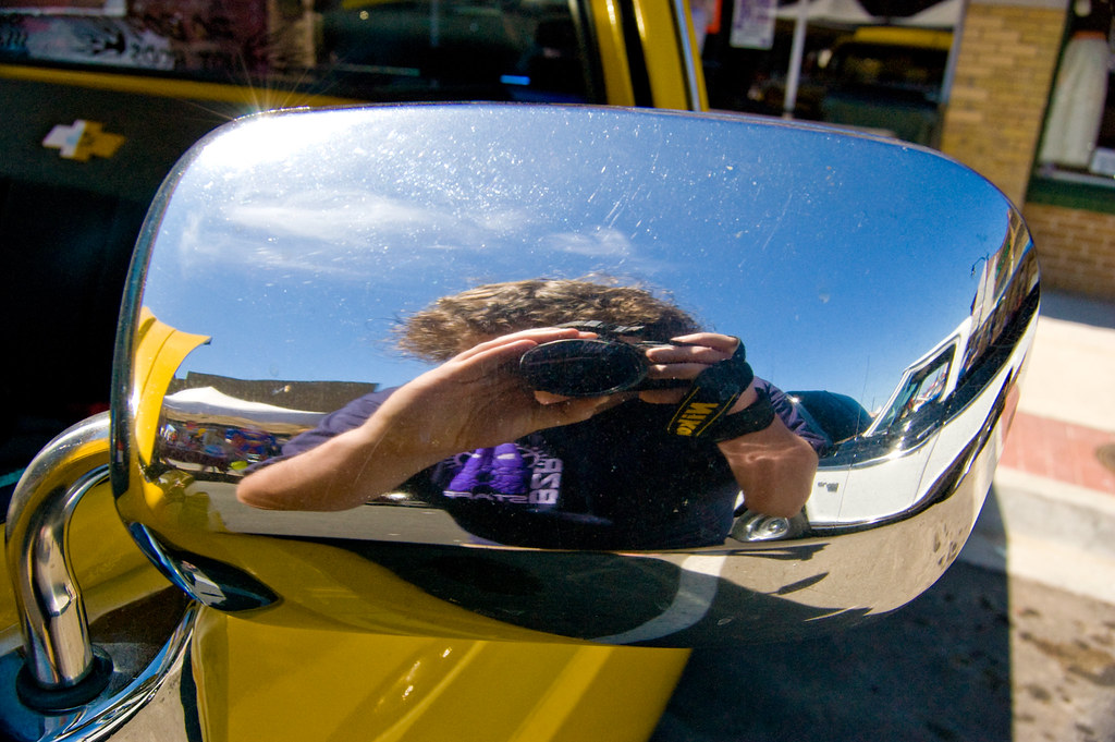 Self-portrait in the outside of a rear-view mirror