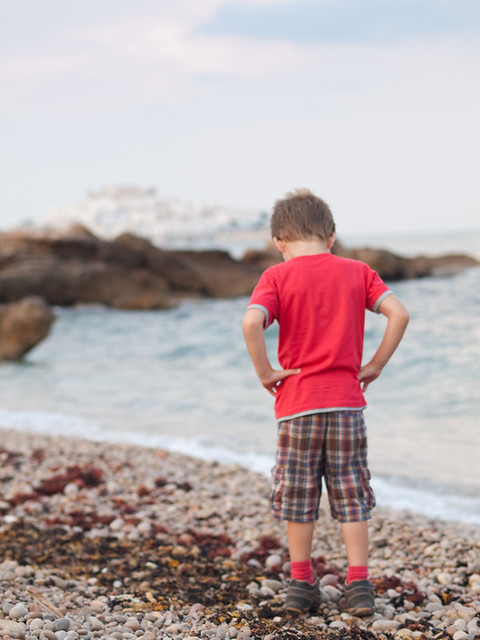 Little boy thinking in a pebbles beach