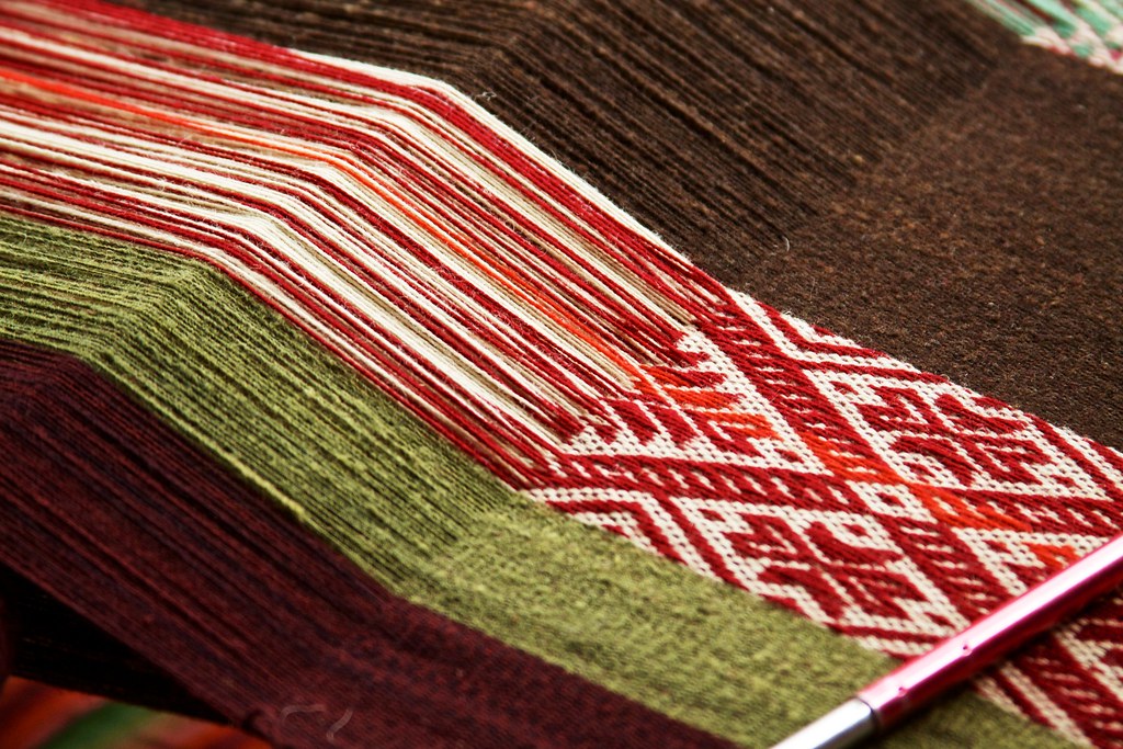 Weaver working a backstrap loom with dyed wool — photo by mckaysavage on Flickr, CC BY 2.0