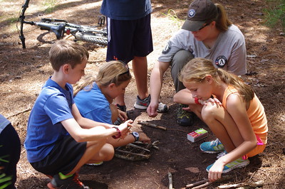 An Americorps volunteer teaches students how to make a fire.