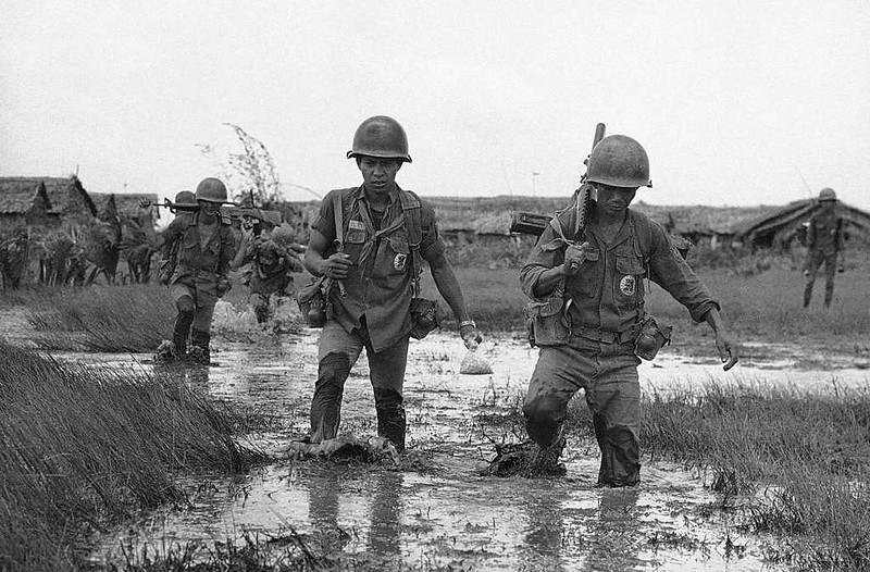 Photo: Soldati sudvietnamiti attraversano una zonna allagata nella provincia meridionale di Camau, 24 agosto 1962. (AP Photo/Horst Faas)