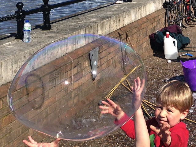 Small Child Trying to Catch a Large Bubble Thames River South Bank London England United Kingdom