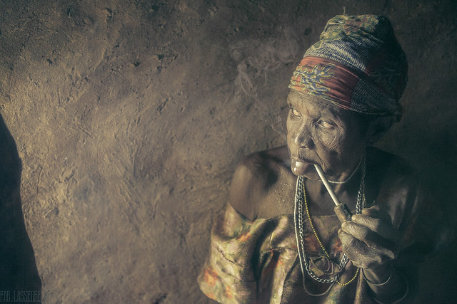 An Old Tamberma woman, protecting herself from the rain in her typical home. Tamberma means 