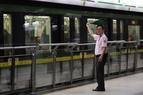 Shanghai Metro platform staff waving the 'all clear' flag to the driver