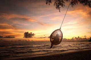 Silhouette woman on a beach swing