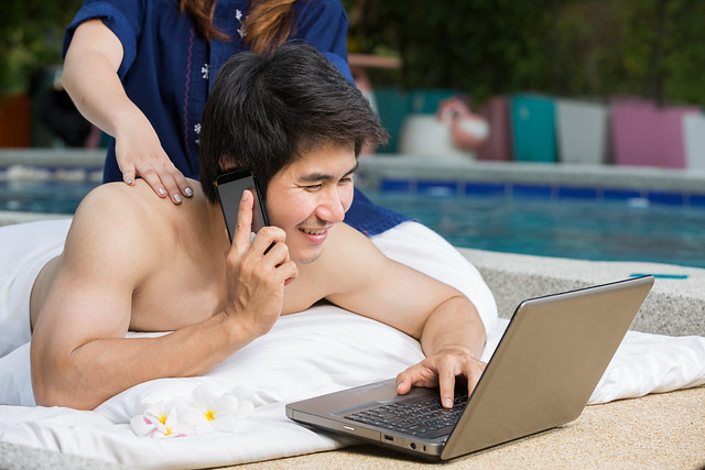 Asian Young masseuse massaging an attractive man in a tropical hotel garden