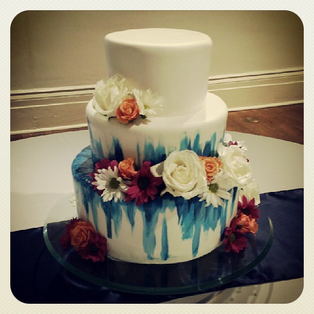 Fresh florals accent this modern wedding cake with painted blue streaks!