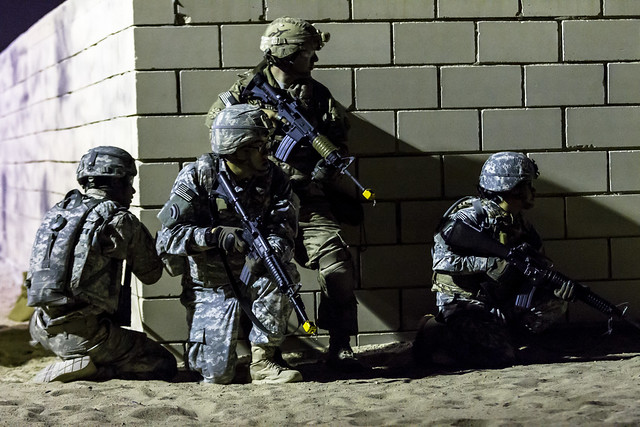 Sgt. Daniel Feng (center kneeling), a signal support systems sergeant with HHC, 42nd Combat Aviation Brigade, positions his team for an assault into a mock compound during his squad's Warrior Leadership Course (WLC) mission the night of July 10, 2014 in C