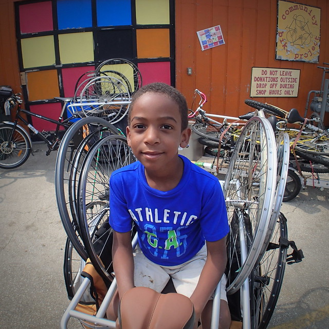nephew helping with bike recycling drop-off at Bloomington's community bike project