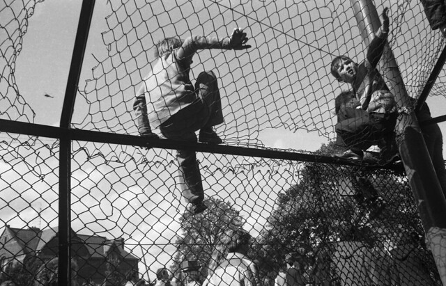 Boys climbing on cage outside pub, Falls Road Belfast 1981