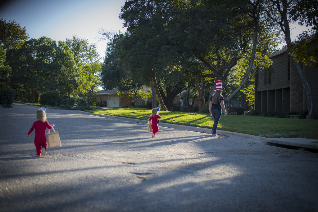 Children in Halloween costumes walking along a residential street