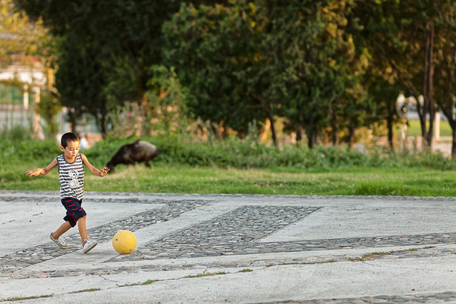 Young boy plays football with yellow ball