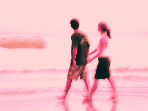 Casal de mãos dadas passeando na praia